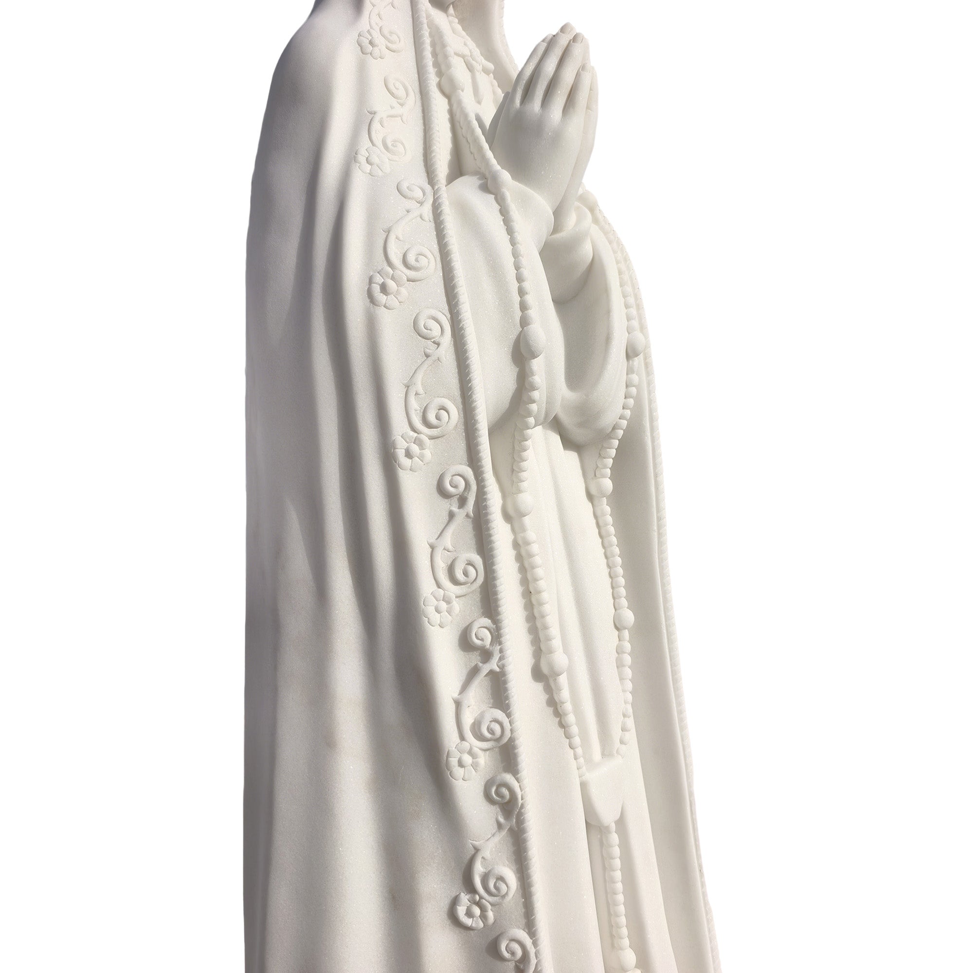Close-up detail of hand-carved marble Our Lady of Fatima statue highlighting rosary and intricate robe patterns, religious art craftsmanship.