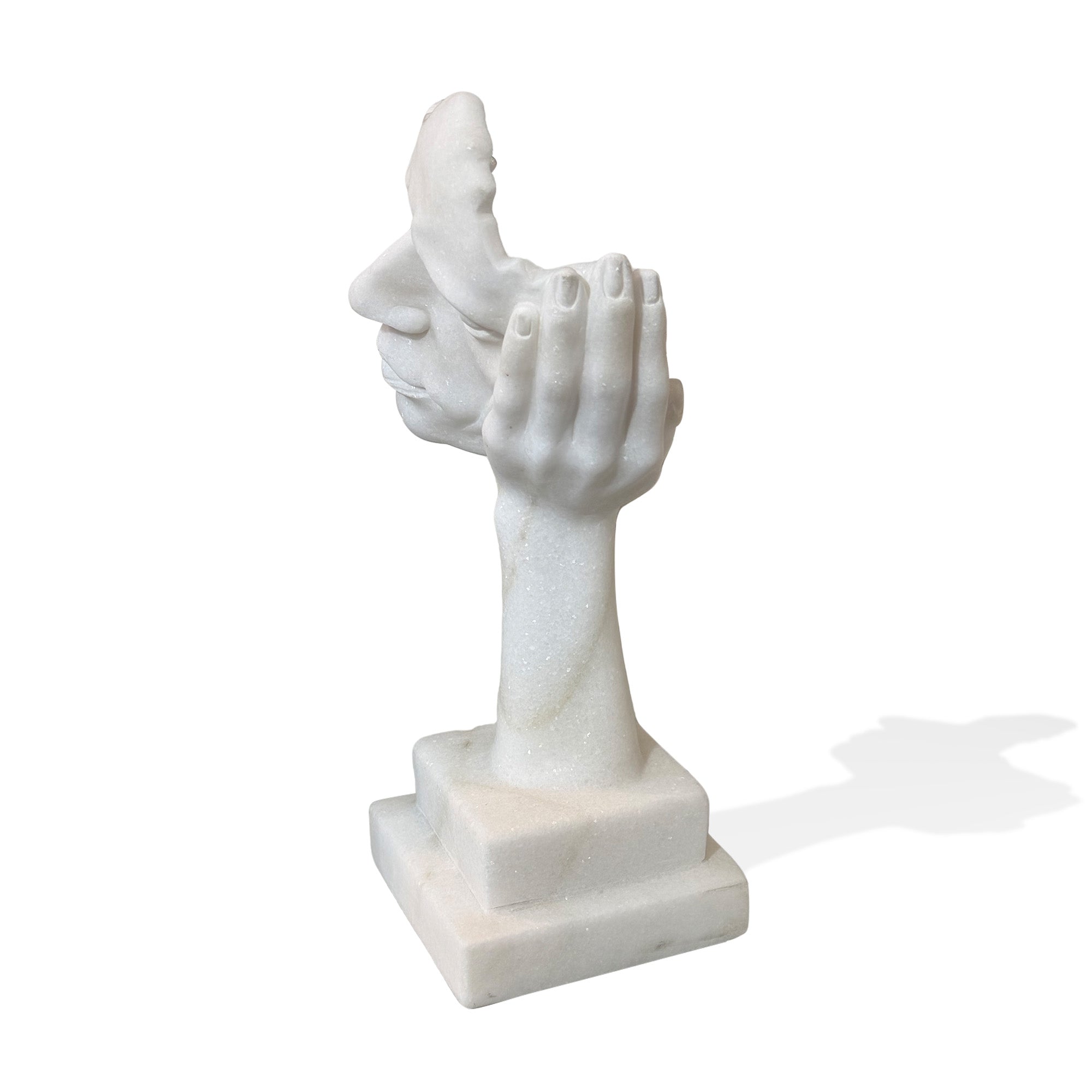 Side view of a white marble abstract head sculpture supported by a carved hand on pedestal base