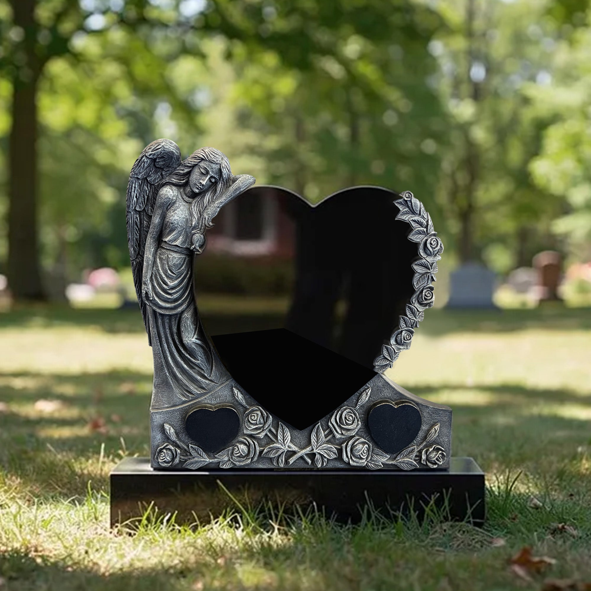 Custom black granite angel heart headstone installed in a cemetery, featuring a polished heart-shaped memorial panel, resting angel relief, and carved rose details