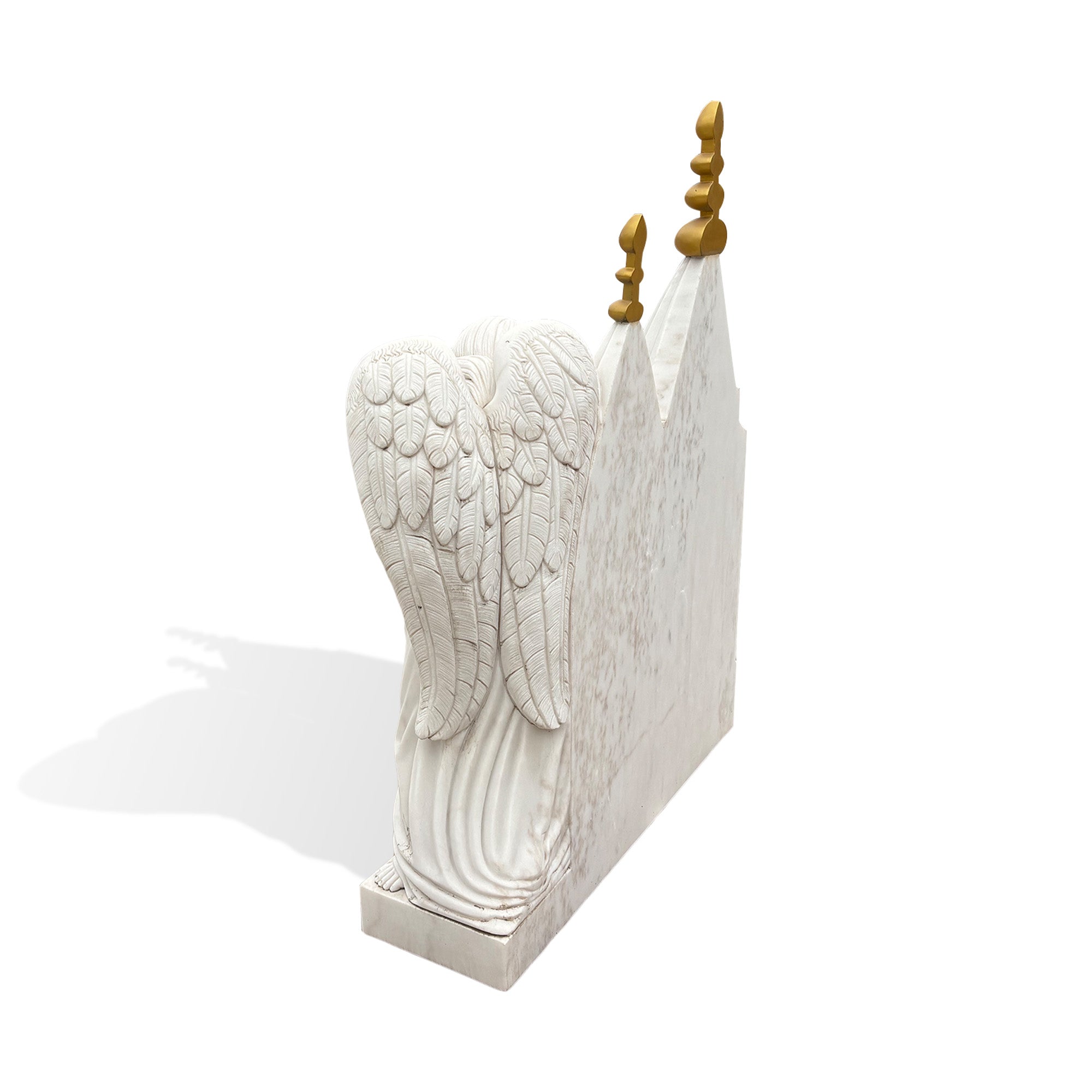 Back view of a solid white marble angel memorial headstone showing deeply carved feathered wings, chapel-style towers, and substantial stone construction