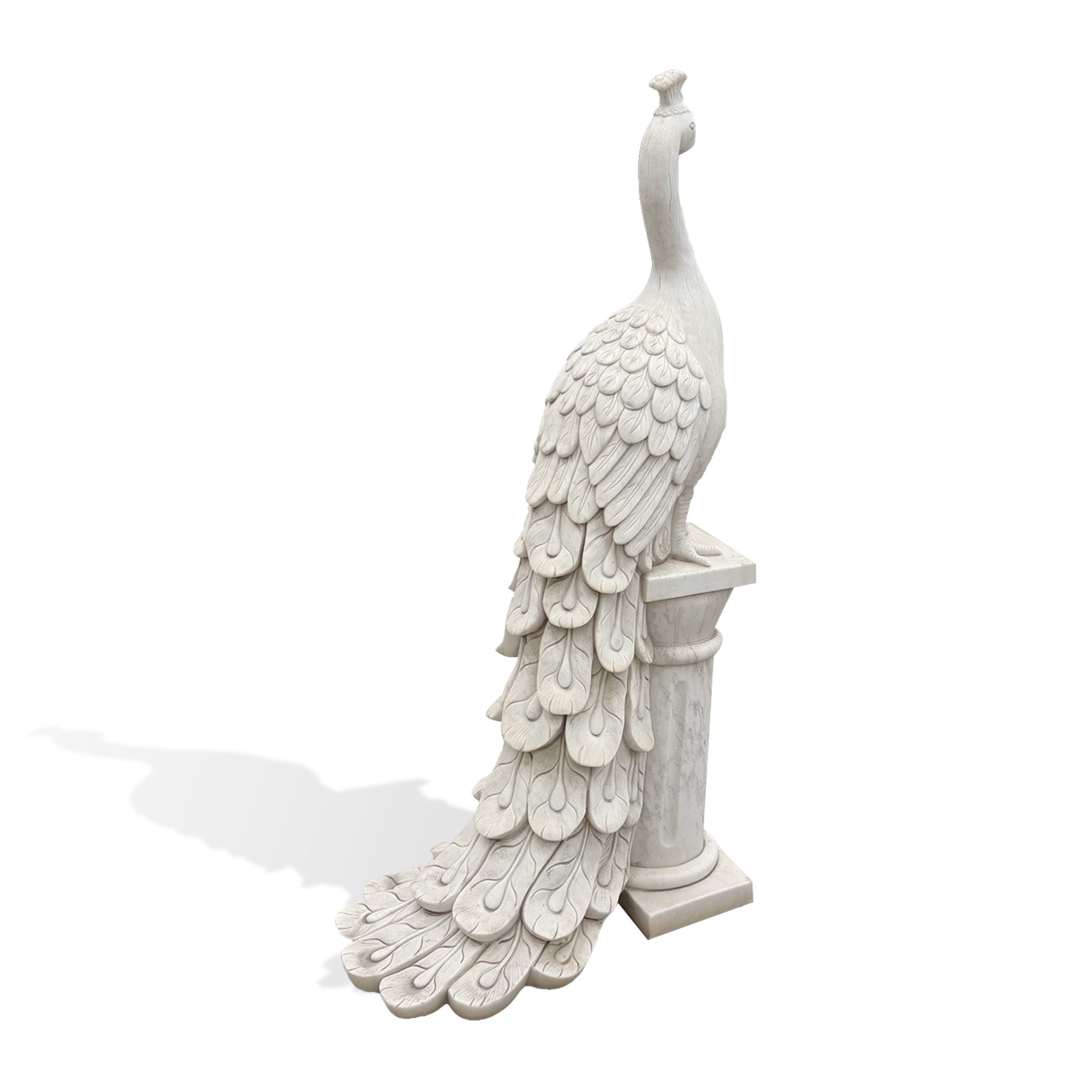 Rear view of a white marble peacock garden statue showing layered feather carving and a long decorative tail