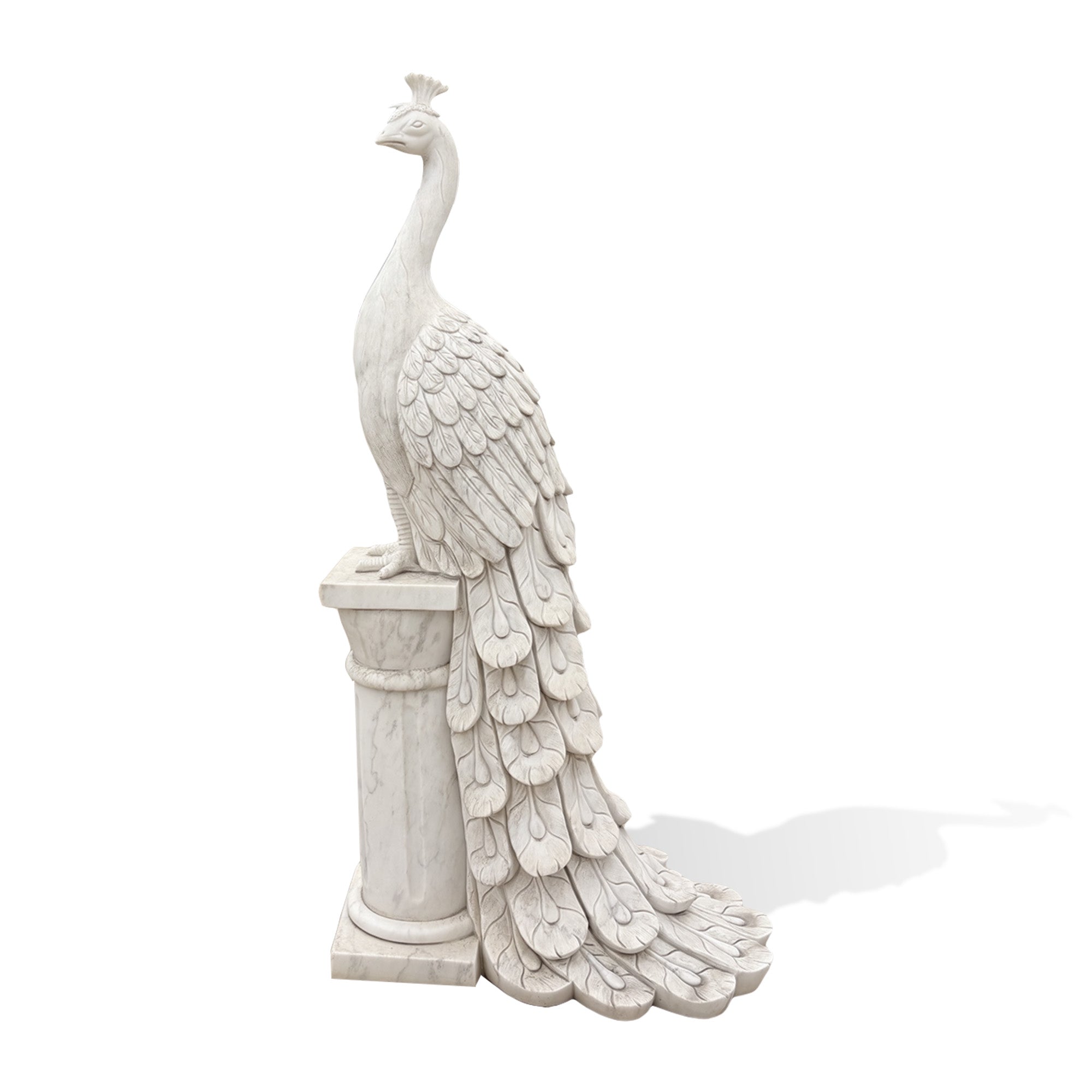 Side view of a white marble peacock statue with detailed feathers, a flowing tail and a classical column pedestal
