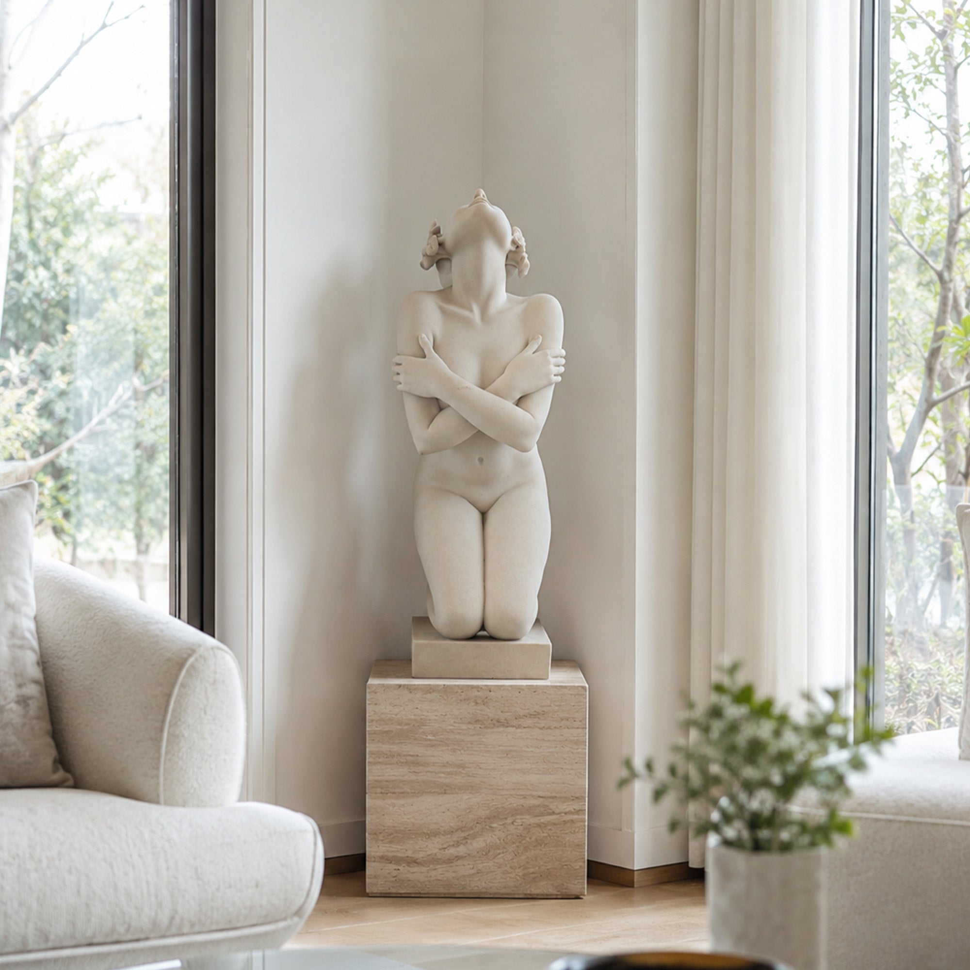Natural marble kneeling female sculpture displayed on a pedestal in a bright modern living room as refined statement art for a luxury interior