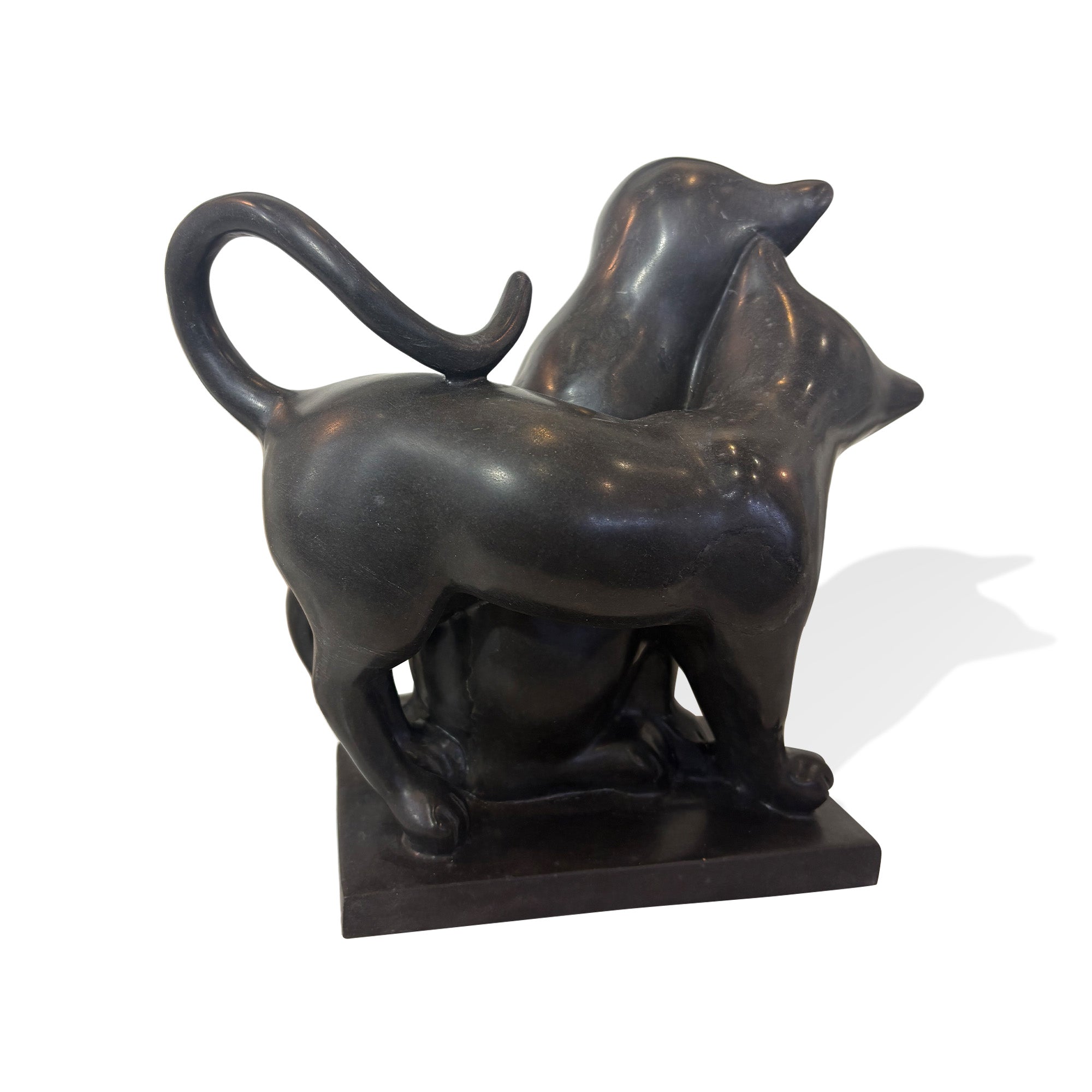 Back view of black stone cat sculpture showing two cats leaning together with raised curved tails and a polished stone finish