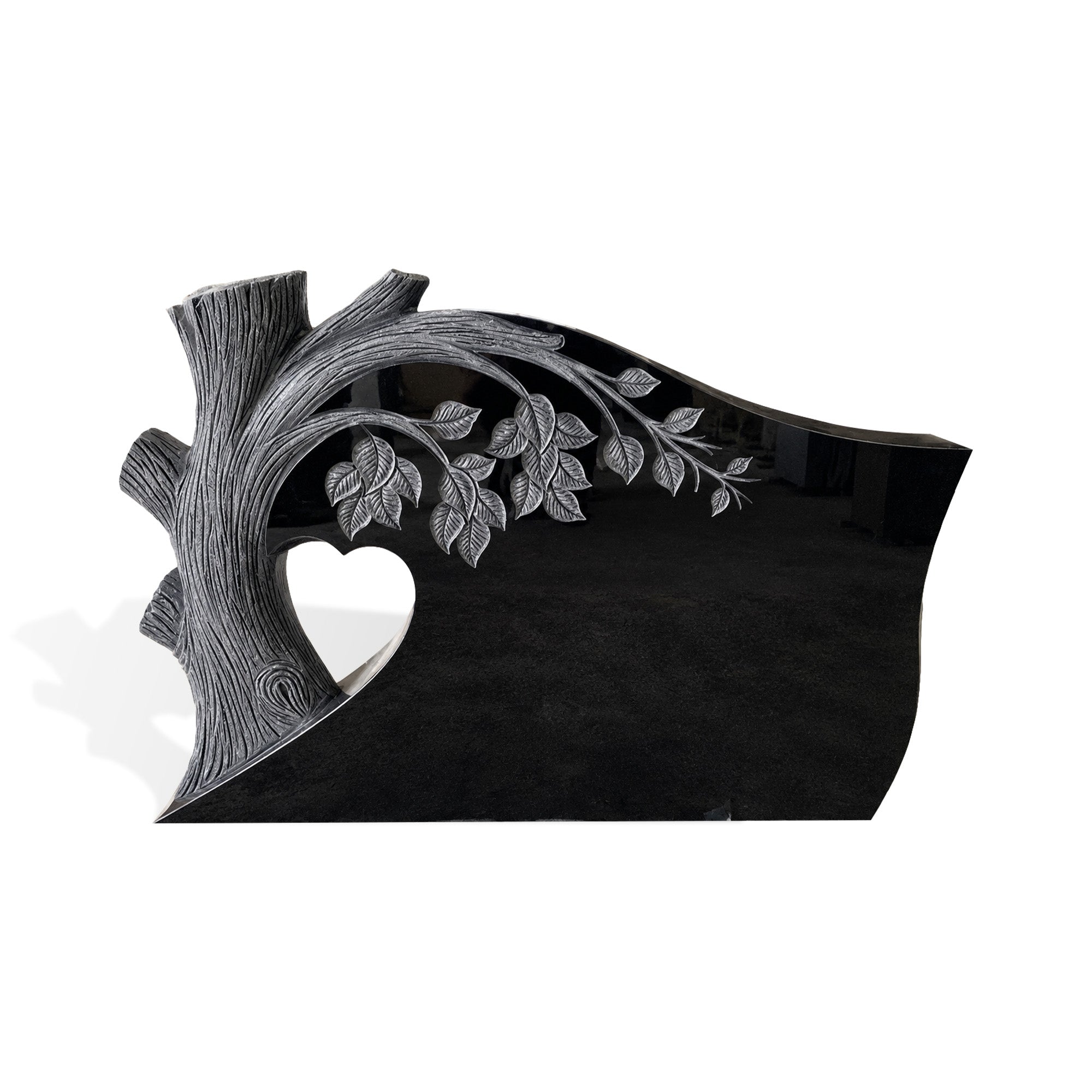 Black granite memorial headstone with carved tree trunk, engraved branches and leaves, heart-shaped cutout, polished black surface, curved top, and white background