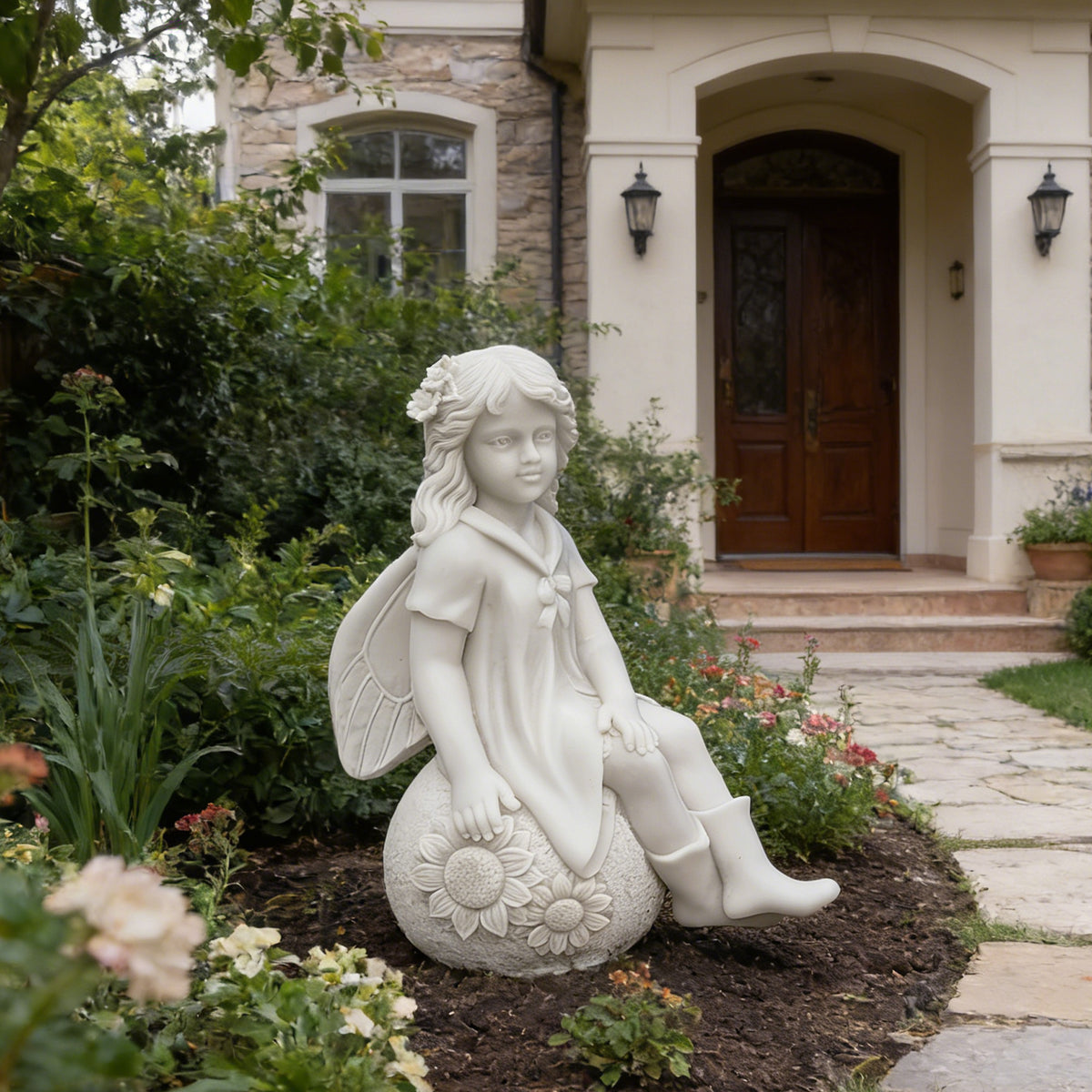 White marble garden fairy statue of a seated girl with wings, a floral hair ornament and sunflower carvings displayed in a landscaped villa flower bed.