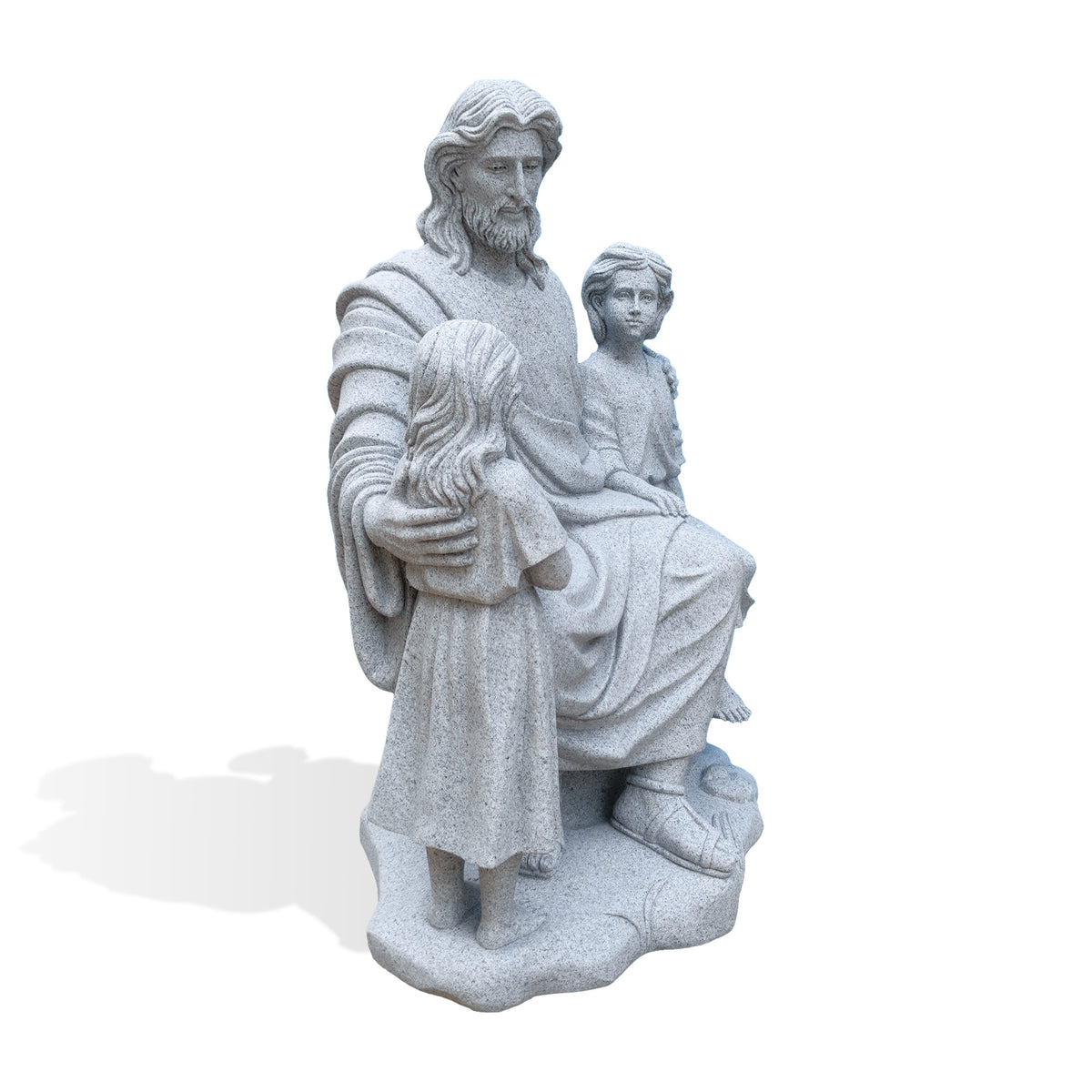 Angled view of a gray granite Jesus and children sculpture with the seated boy in the foreground, showing his bare feet, Jesus’ hand around his shoulder and the standing girl opposite. Carved robe folds, sandals and rock-like seating are visible against a white background.