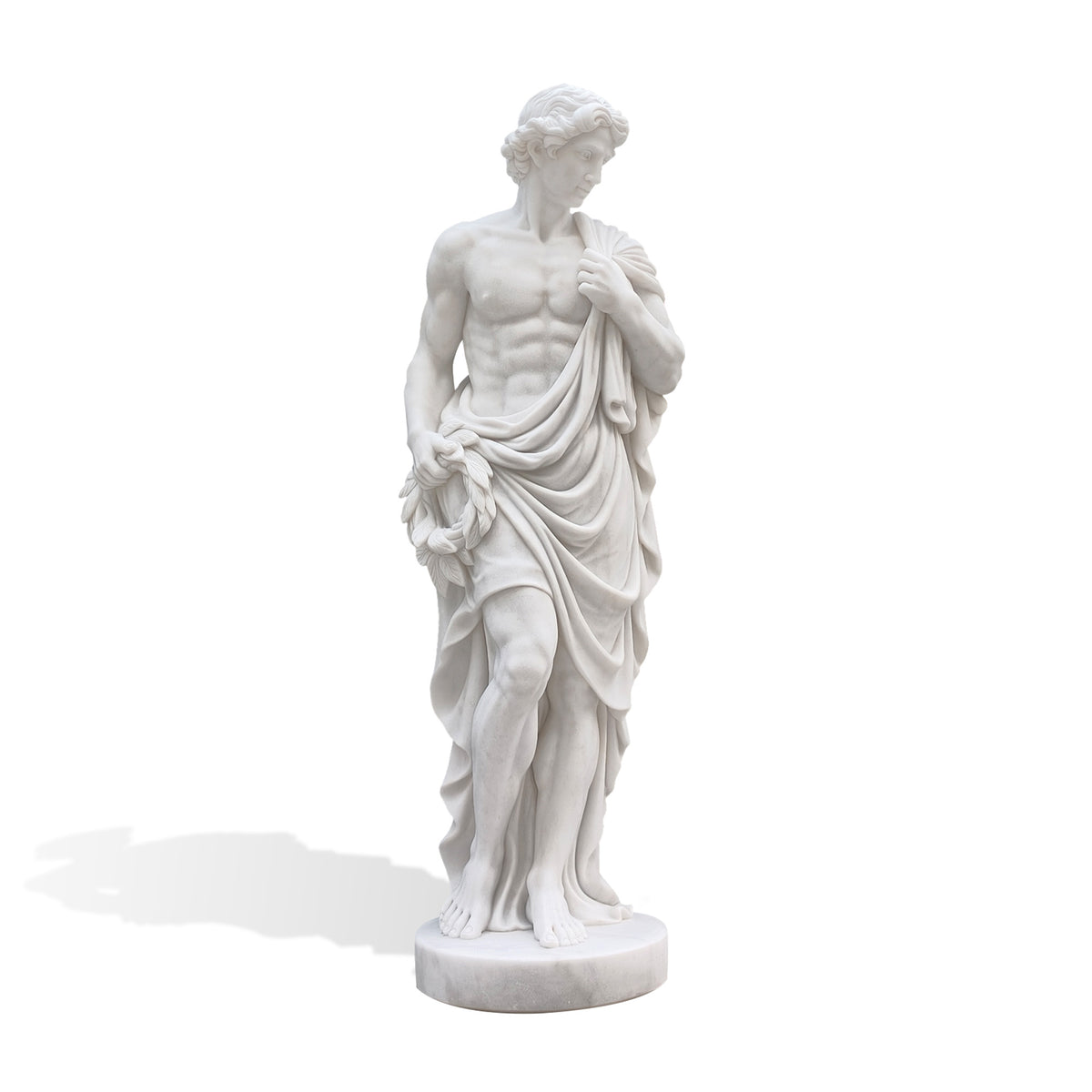 Front view of a white marble male statue with wavy hair, a gently turned head and a defined bare torso. One hand holds drapery at the shoulder while the other carries a laurel wreath beside the hip, with flowing fabric surrounding the legs above a circular base.