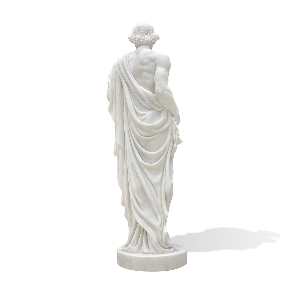 Rear view of a classical white marble male statue, showing wavy hair, a partially exposed muscular back and deeply carved drapery falling from one shoulder to the feet. The figure stands on a round marble base against a white background.