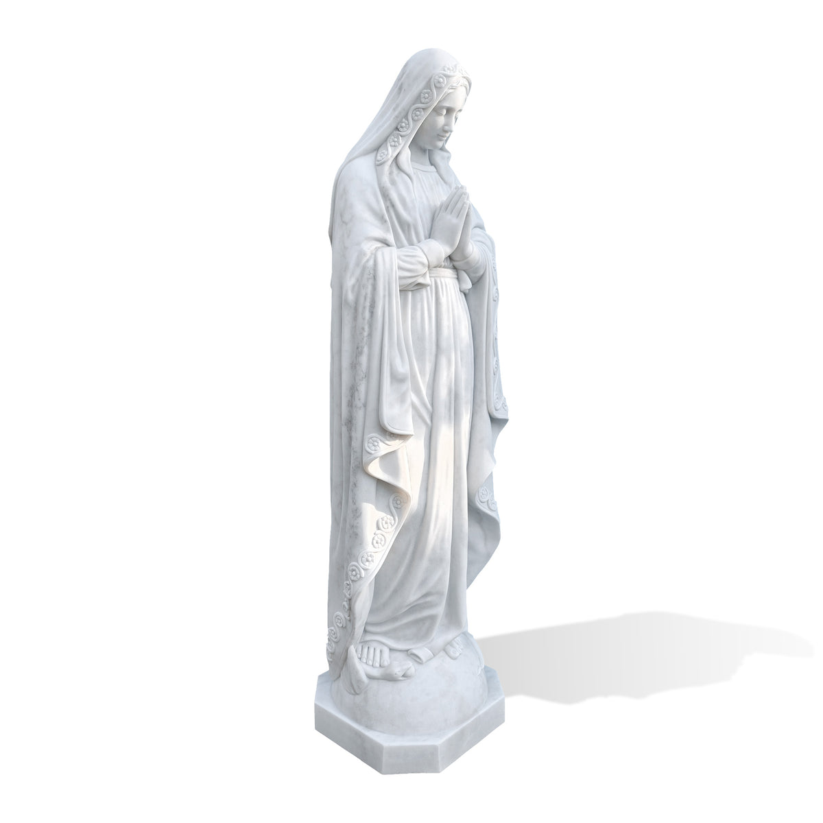 Three-quarter view of a white marble Virgin Mary statue with a bowed head and hands joined in prayer, wearing a long robe and a veil edged with carved flowers and curling vines. Subtle gray veining runs through the mantle above a faceted base against a white background.