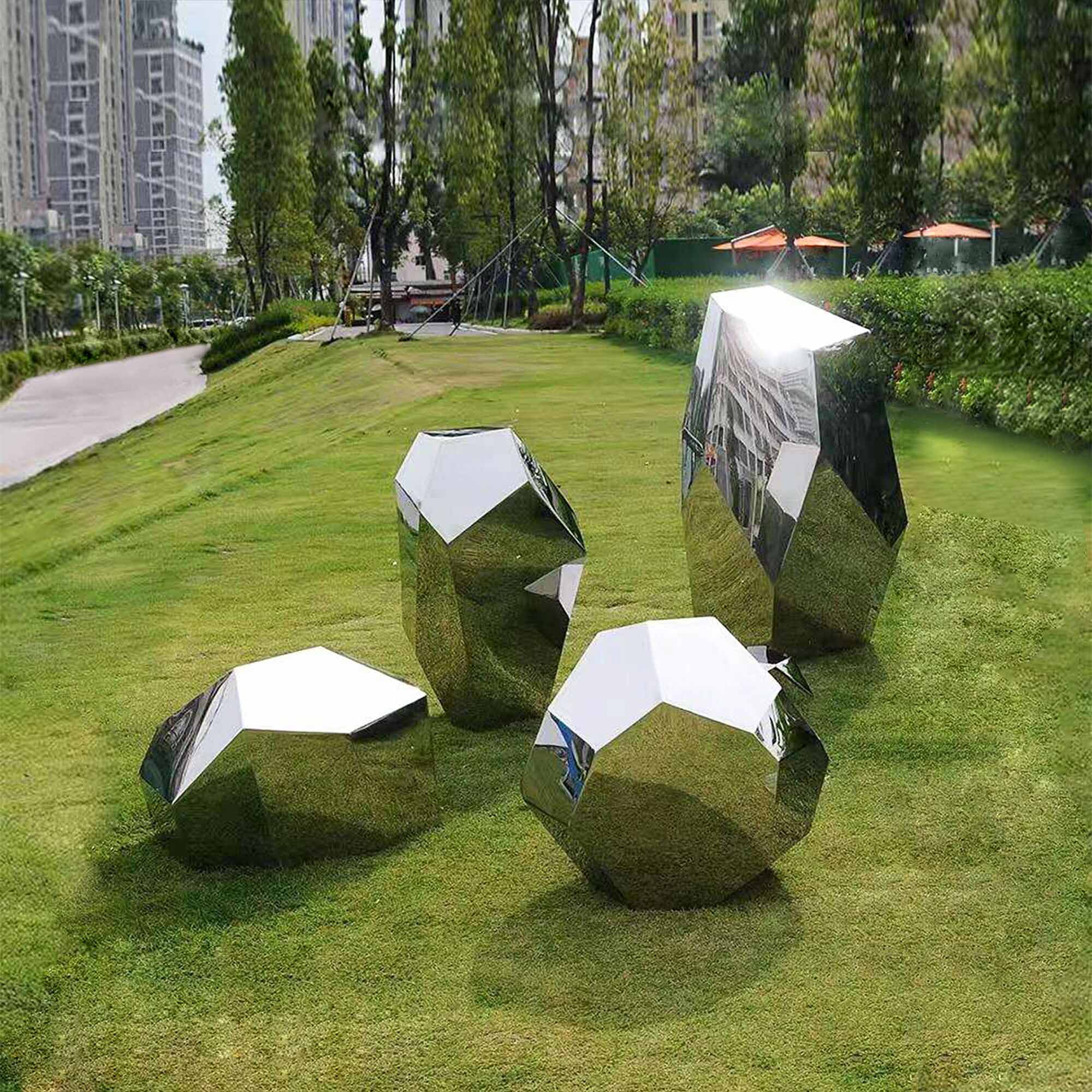 Polished stainless steel geometric block sculptures in various polygonal shapes displayed on a lawn in front of a house