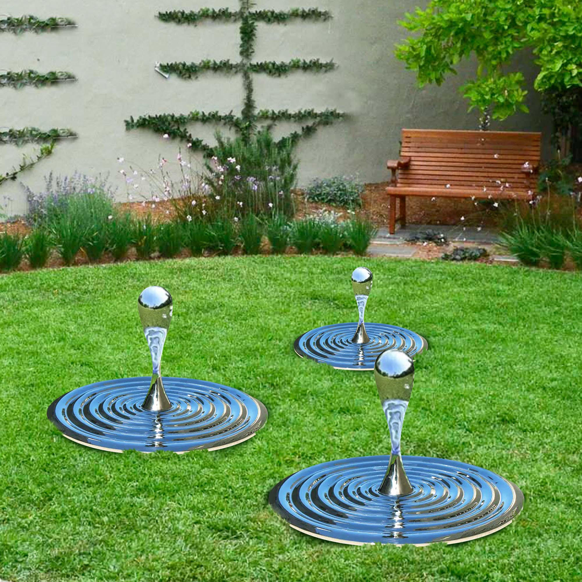 Polished stainless steel water drop sculptures with concentric ripple bases displayed on a green lawn, reflecting the surroundings in a garden setting.