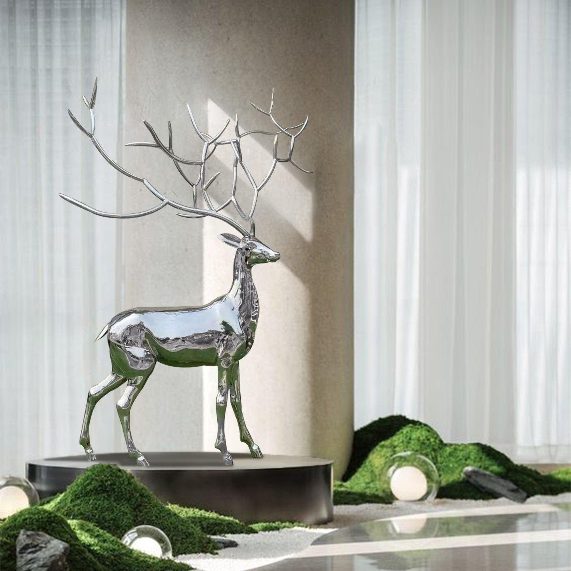 High-polished stainless steel elk sculpture placed indoors on a pedestal with intricate antlers and a glossy reflective surface