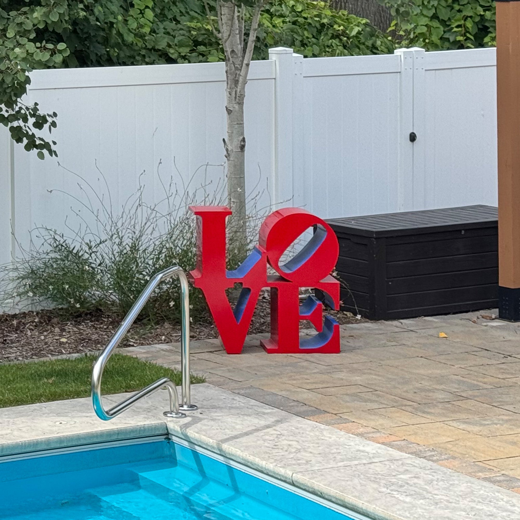 painted red and blue love letter sculpture displayed beside swimming pool as modern outdoor garden decor