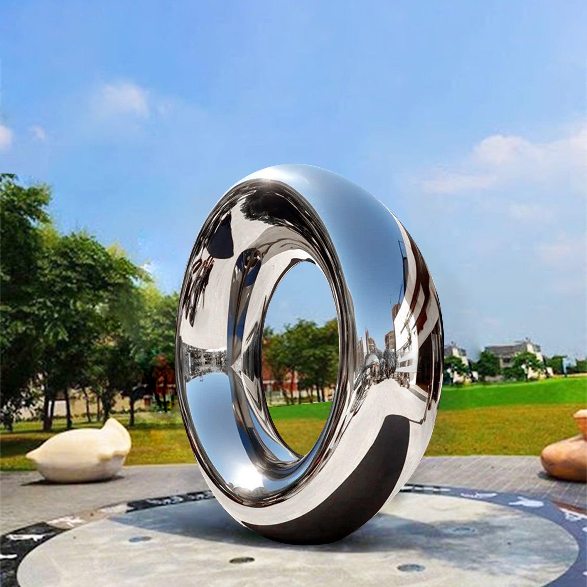 large circle ring mirror metal sculpture standing tall in public garden