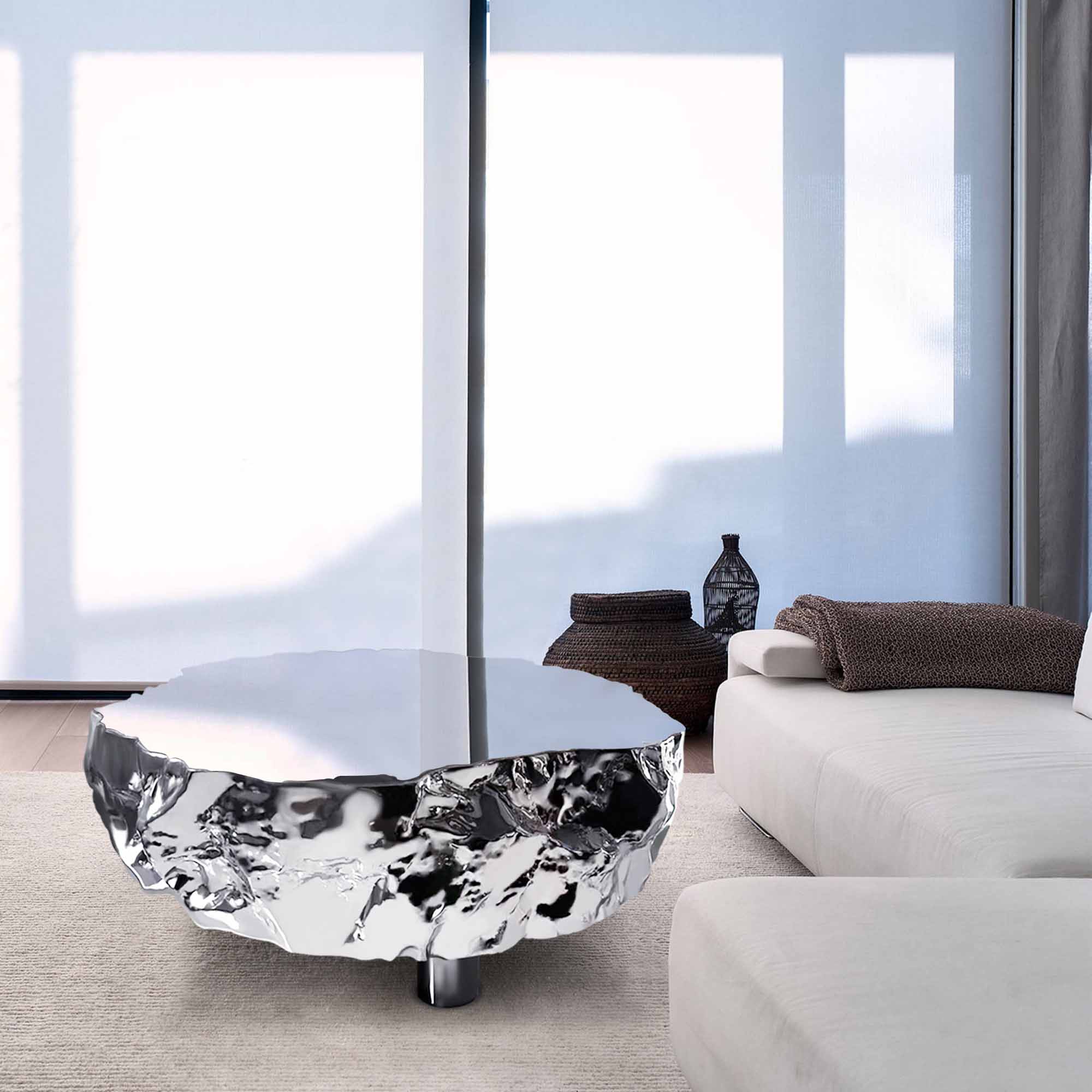 Modern stainless steel coffee table with a polished mirror surface and textured base, placed in a luxury living room setting