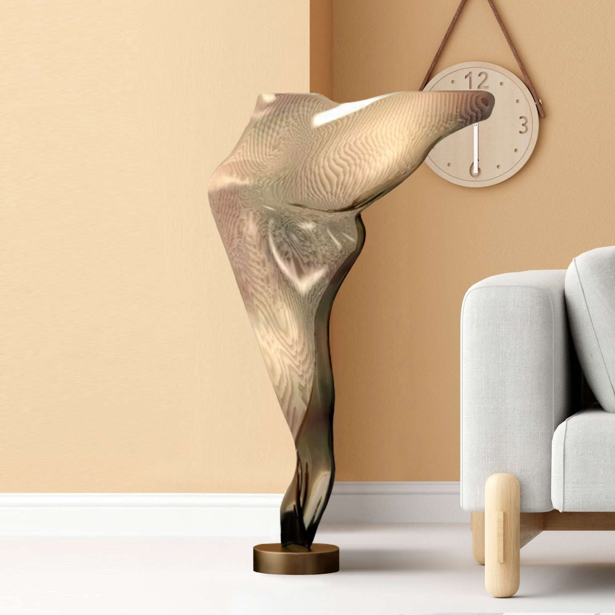 Abstract gold metal floor sculpture with polished finish, displayed in a modern living room setting.