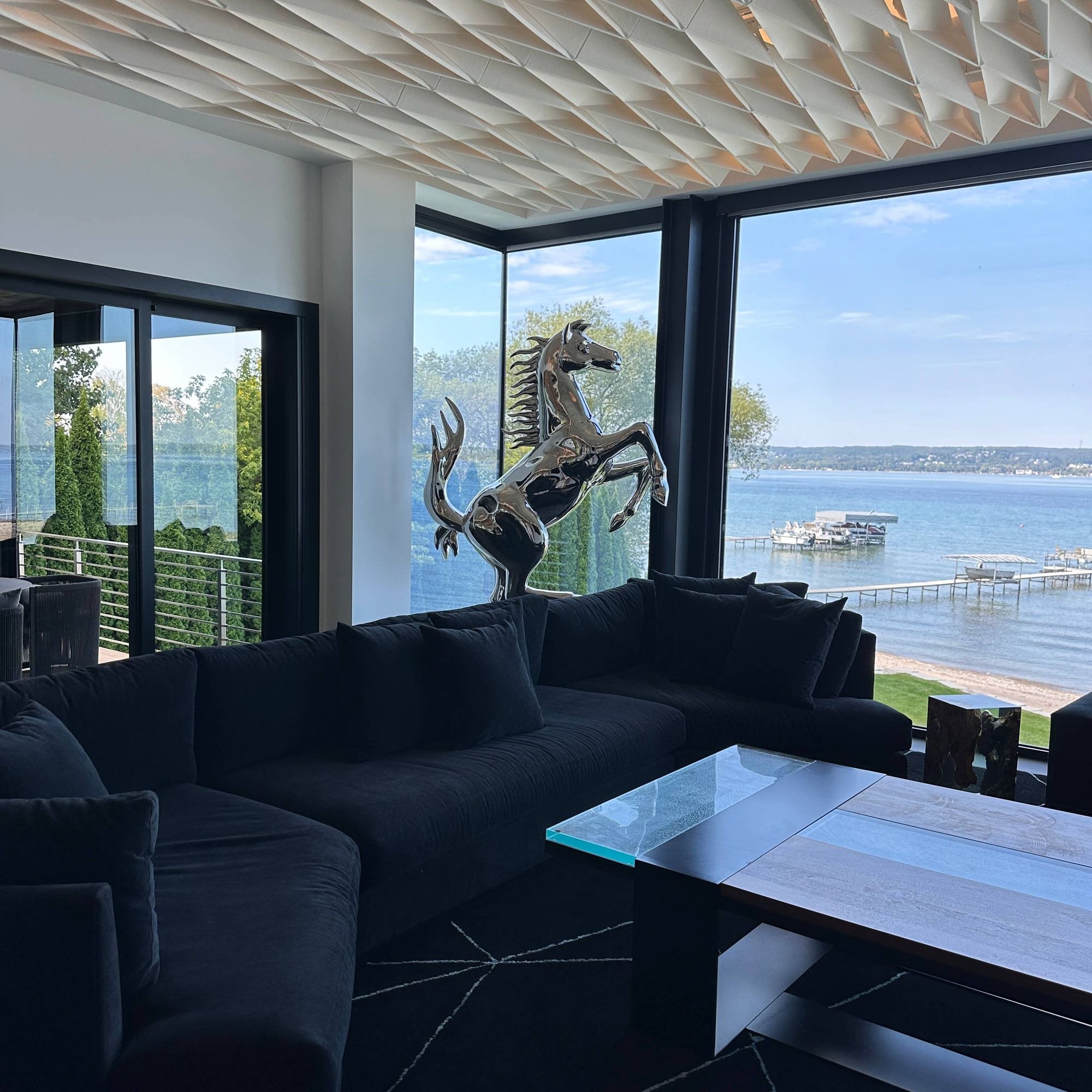 large stainless steel horse artwork displayed in modern home in front of black sofa