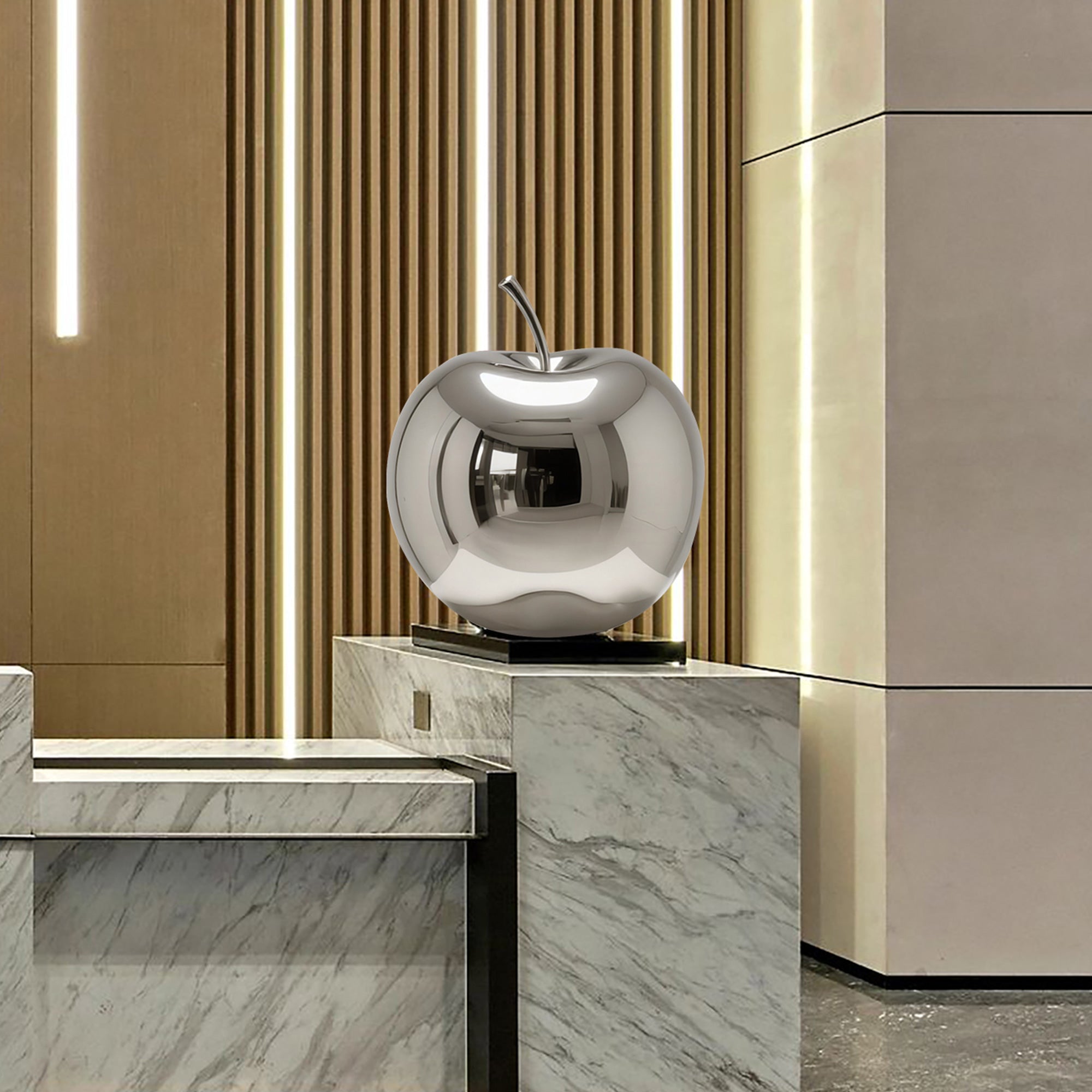 Silver apple stainless steel sculpture on a marble surface with a modern interior background