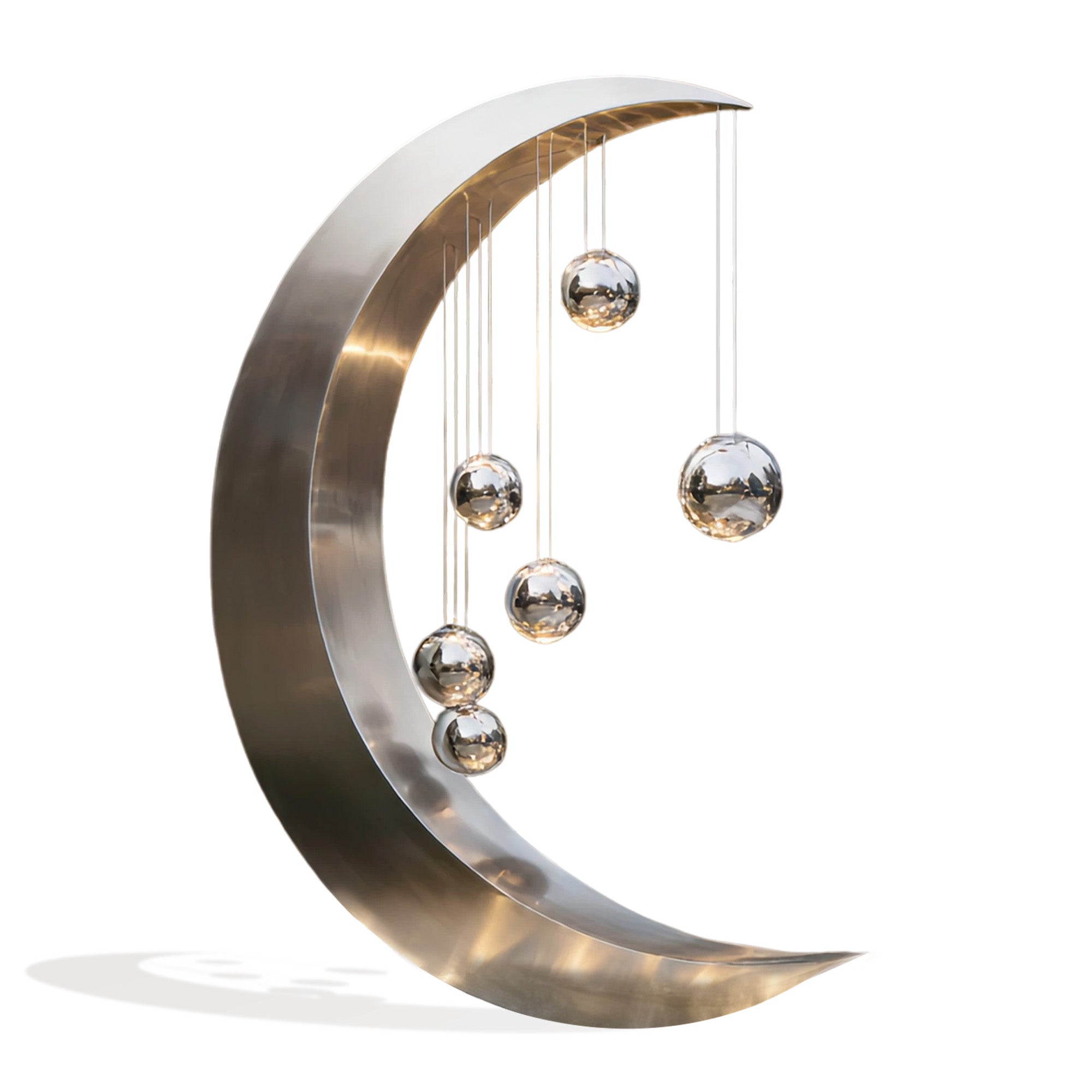 Abstract moon-inspired stainless steel sculpture with a brushed finish and hanging metallic spheres, showcasing a minimalist crescent form for modern outdoor and interior decor.