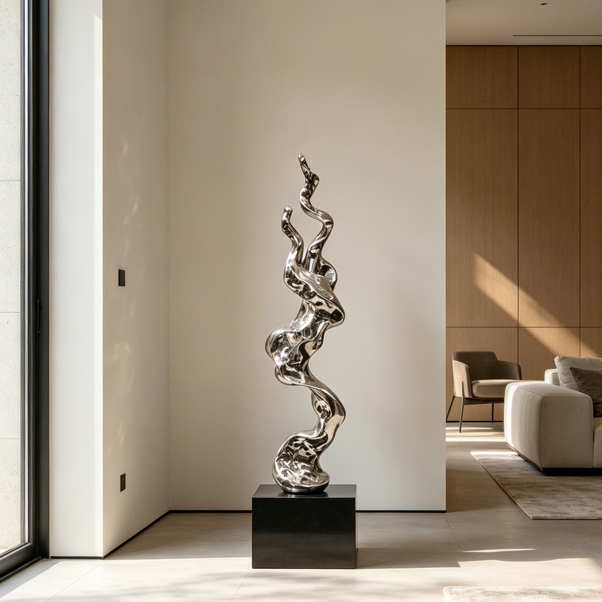 Polished mirror finish abstract sculpture on a black pedestal in a modern interior setting