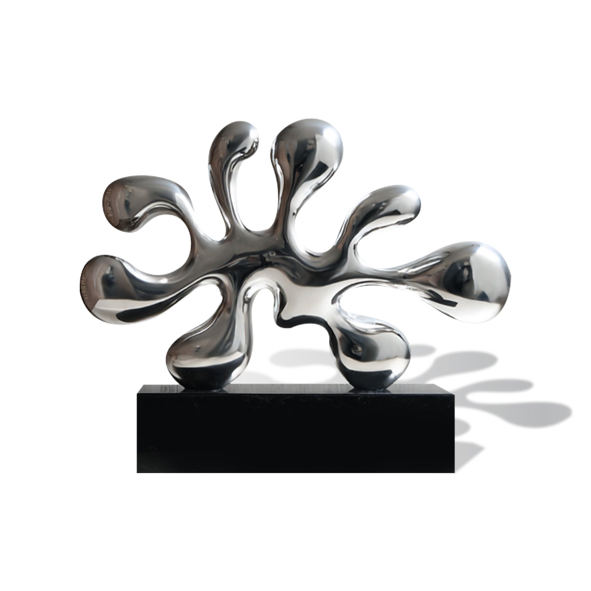 Front view of a mirror polished stainless steel liquid splash statue on a black rectangular base with rounded droplet tips, flowing abstract arms, and reflective silver finish on a white background.