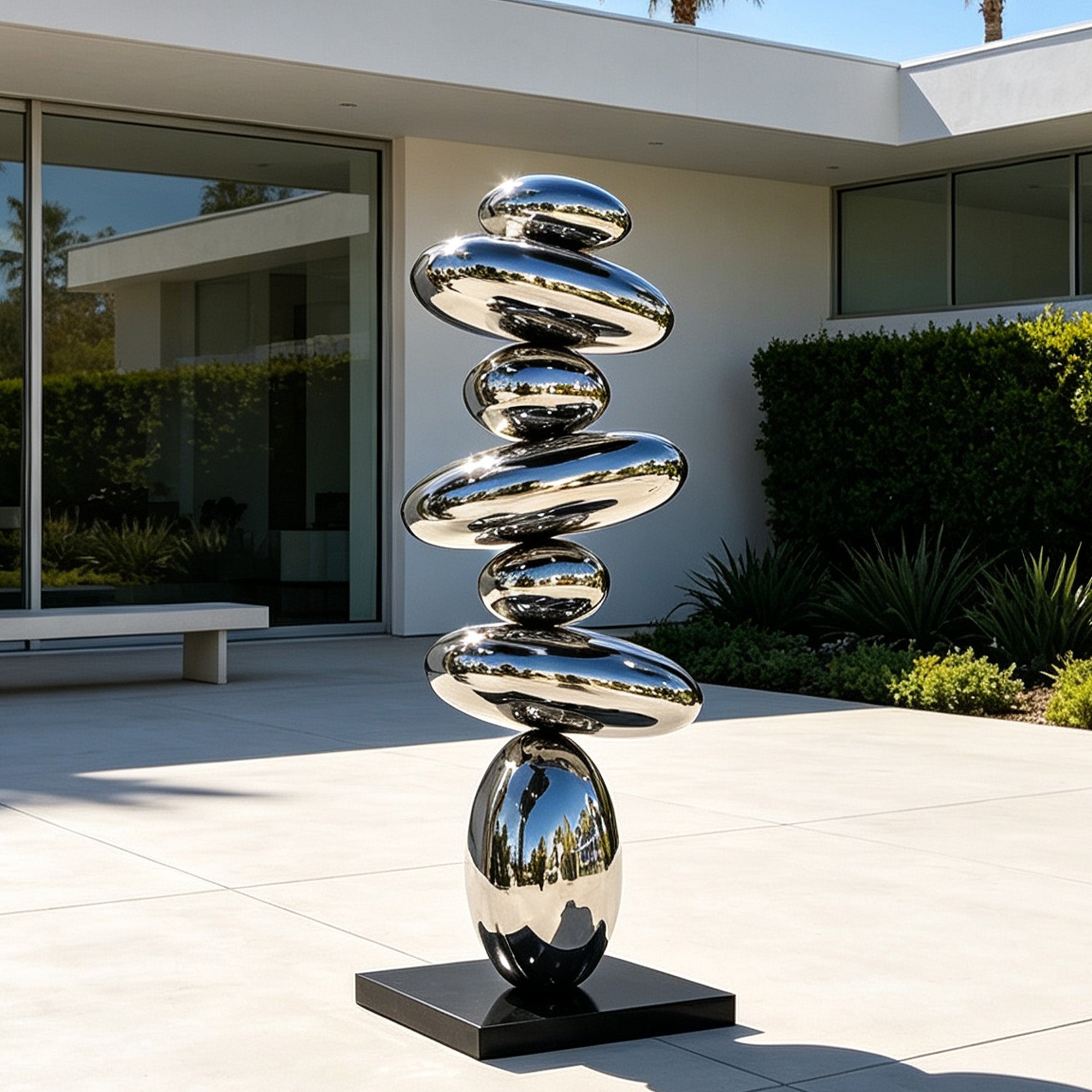 Mirror polished stainless steel balancing pebble sculpture displayed in a modern  garden