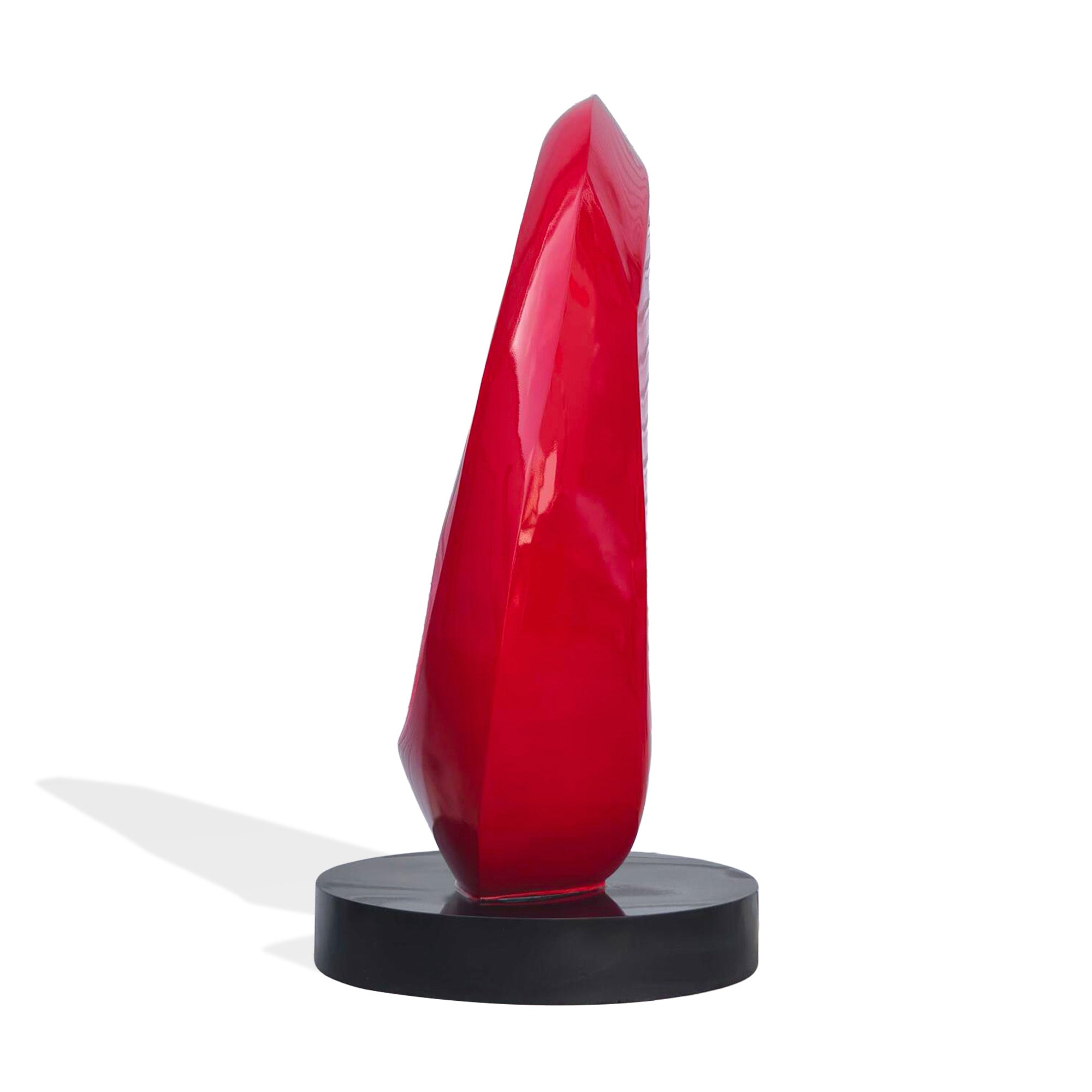 Side profile of glossy red painted stainless steel abstract oval loop sculpture, sleek modern decor piece on black circular base.